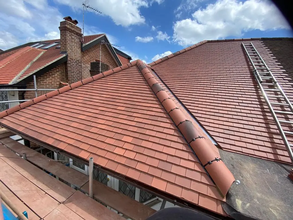 Red tiled roof with a visible chimney and sky in the background.